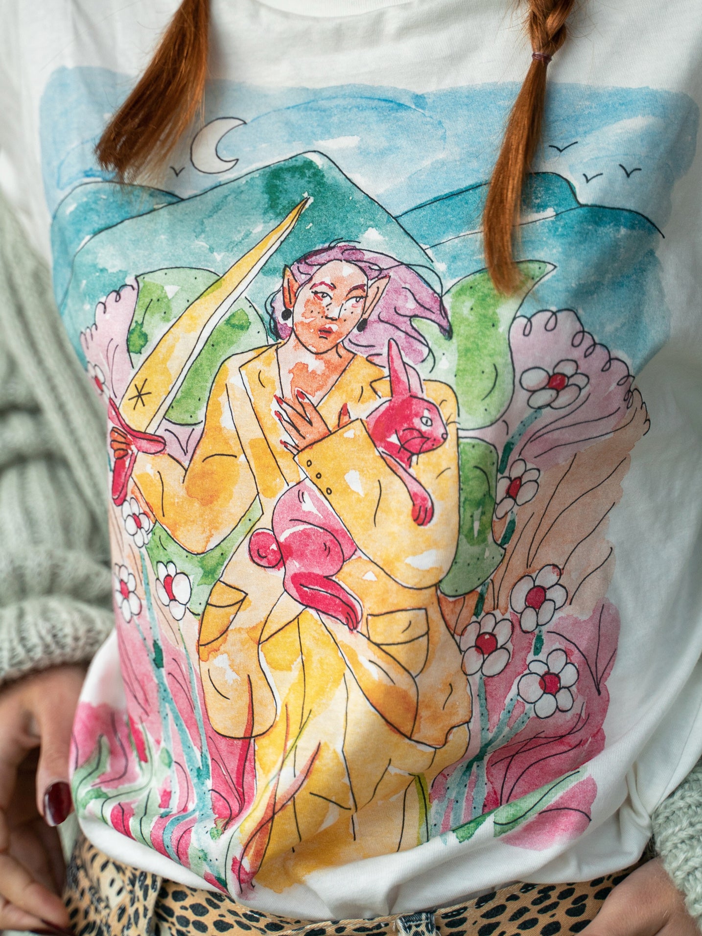 Women's short sleeve 100% cotton shirt featuring a woman warrior surrounded by highlands and nature, designed by Latino artist Ana Paula Machuca. Made in Peru